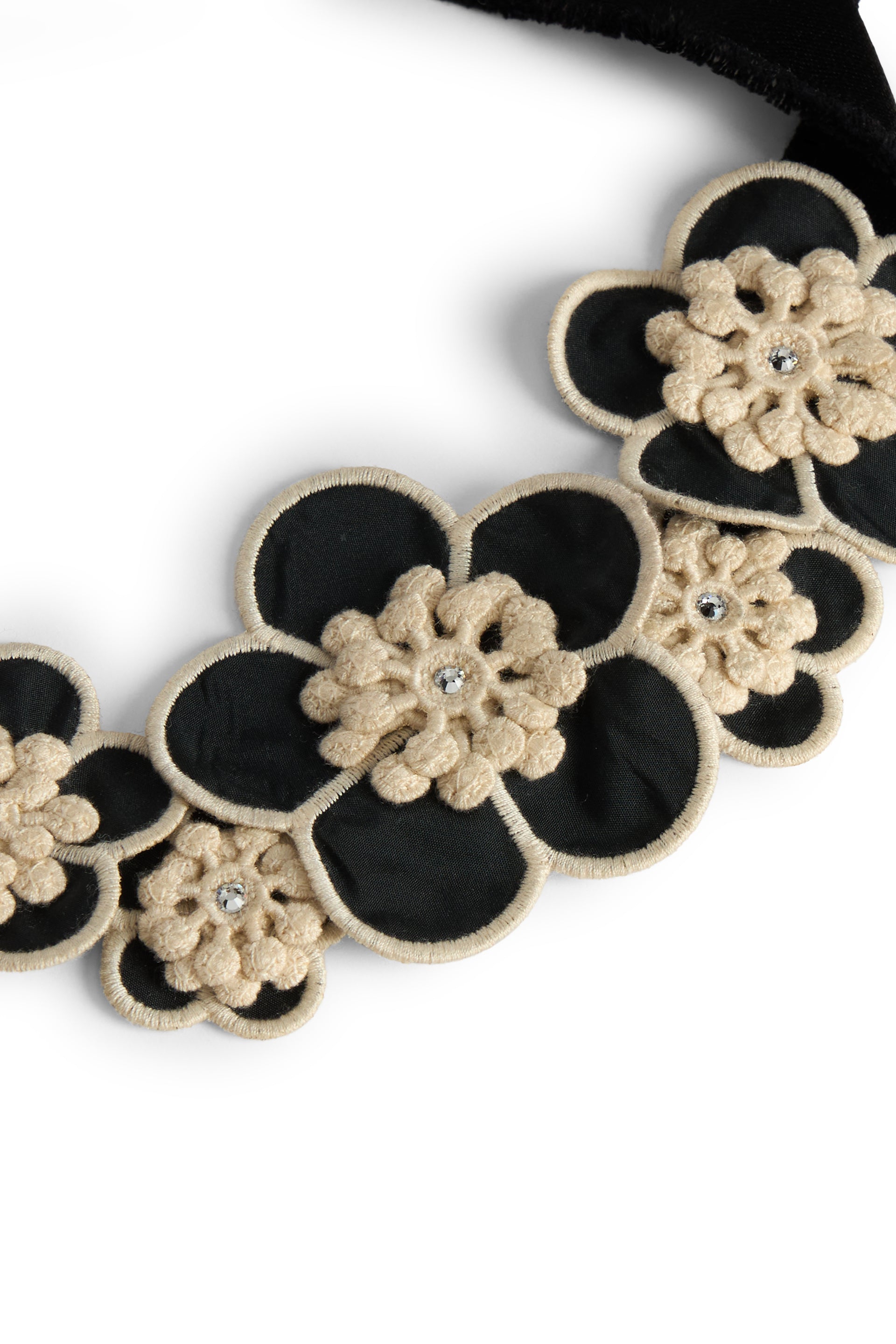 Elegant floral necklace with black ribbon and contrasting beige elements.